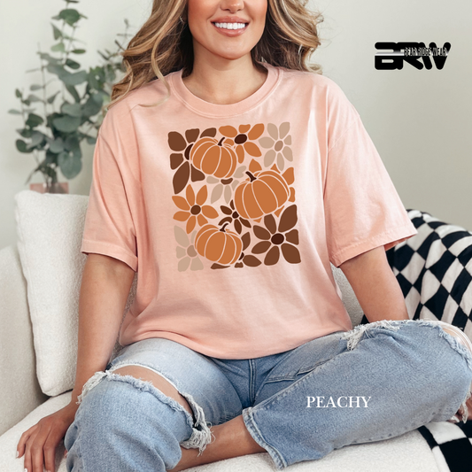 Person wearing a peach t-shirt with pumpkin design sitting on a couch.