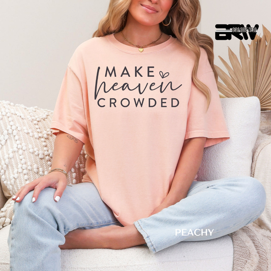 Person wearing a peach t-shirt with 'MAKE HEAVEN CROWDED' text, sitting on a couch.