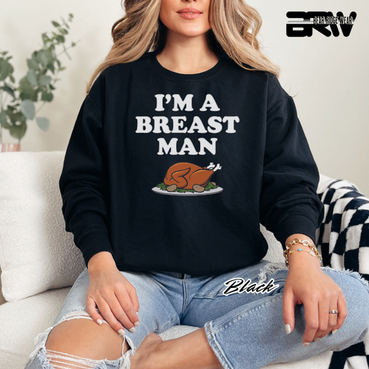 Person wearing a black sweatshirt with 'I'm a Breast Man' text and graphic, sitting on a couch.