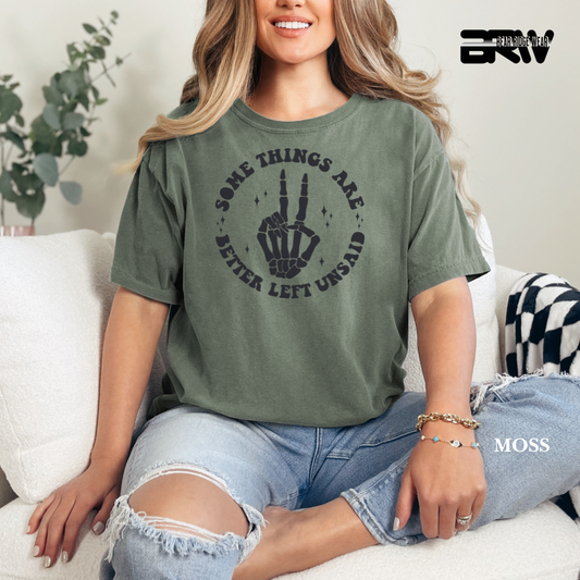 Woman wearing a green t-shirt with a graphic design sitting on a couch.