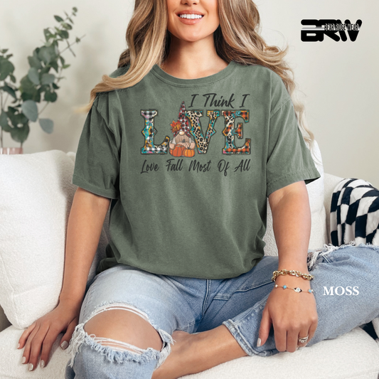 Woman wearing a green t-shirt with a colorful design and text, sitting on a couch. FALL GRAPHIC DESIGN 