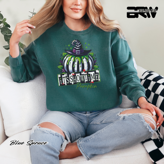 Person wearing a green sweatshirt with a pumpkin design and text, sitting on a couch. ITS SHOWTIME FALL AND HALLOWEEN SWEATSHIRT 