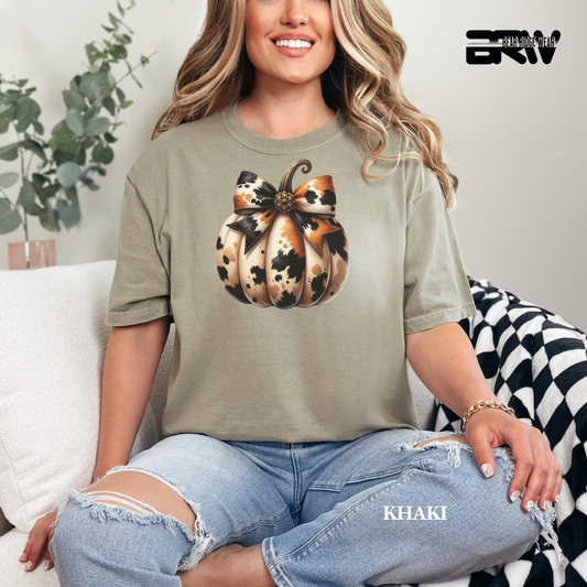 Woman wearing a green t-shirt with a pumpkin design, sitting on a couch.