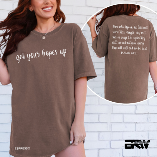 Brown t-shirt with text 'get your hopes up' on front and back, worn by a person against a white brick wall.