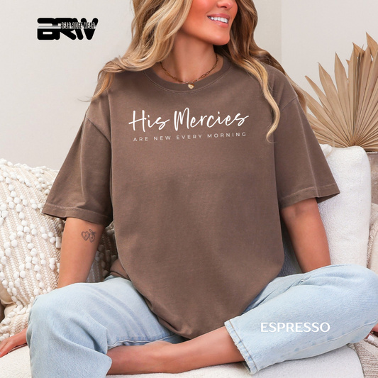 Person wearing an espresso t-shirt with text, sitting on a couch. HIS MERCIES AR NEW EVERY MORNING FAITH TEE