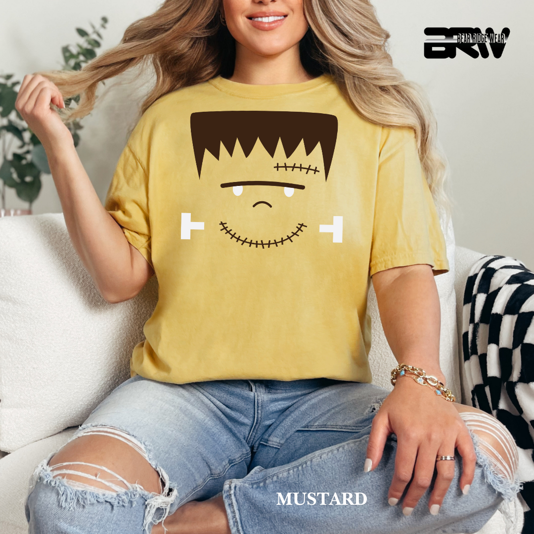 Person wearing a mustard yellow t-shirt with a cartoon character design, sitting on a couch.