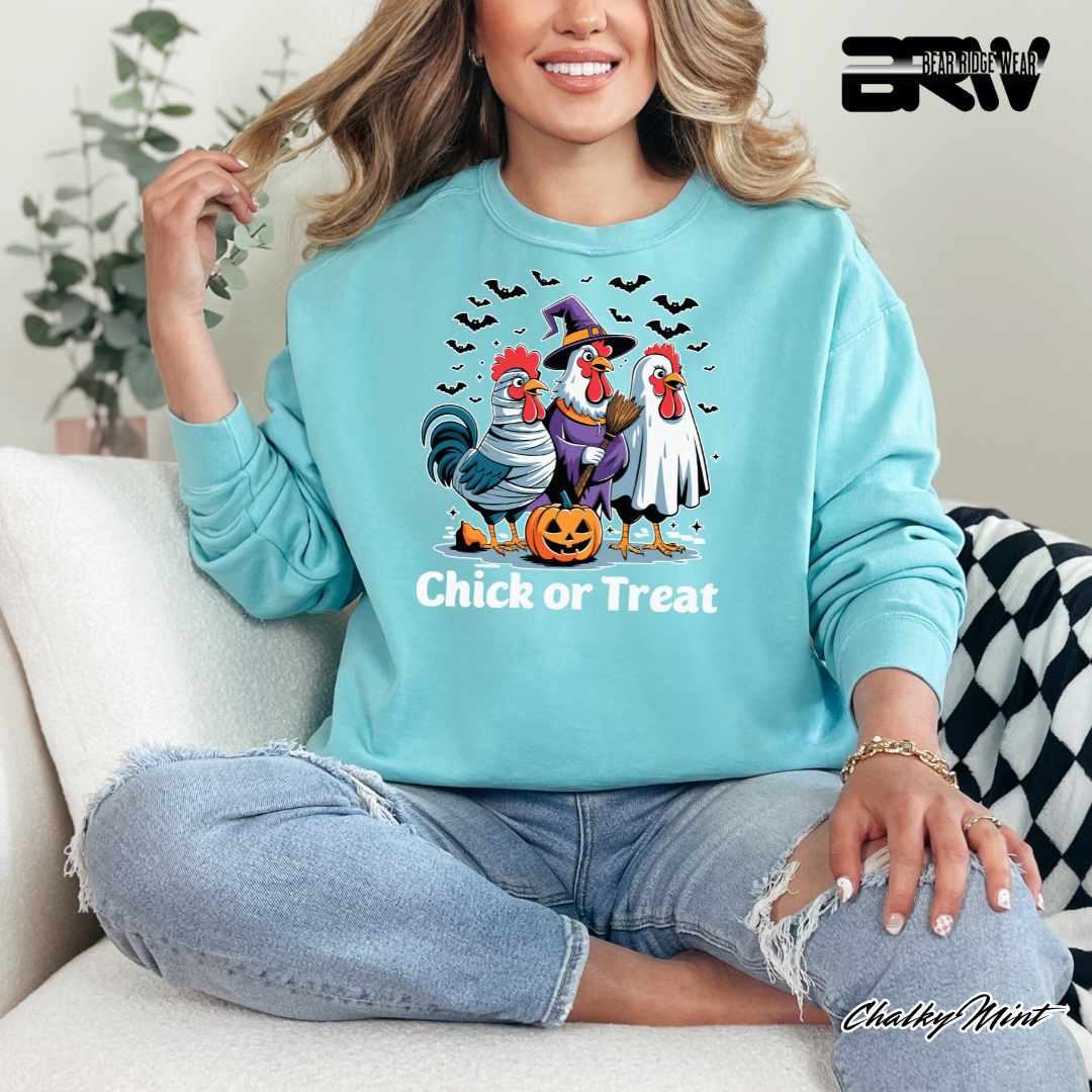 Person wearing a light blue sweatshirt with Halloween-themed chicken design and 'Chick or Treat' text.