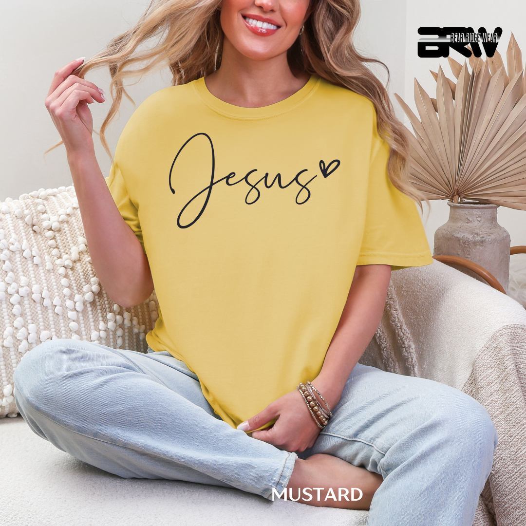 Woman wearing a yellow t-shirt with 'Jesus' printed on it, sitting on a couch.