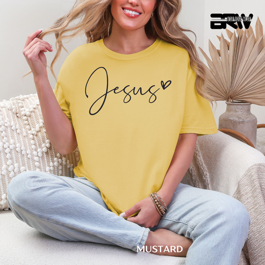 Woman wearing a yellow t-shirt with 'Jesus' printed on it, sitting on a couch.