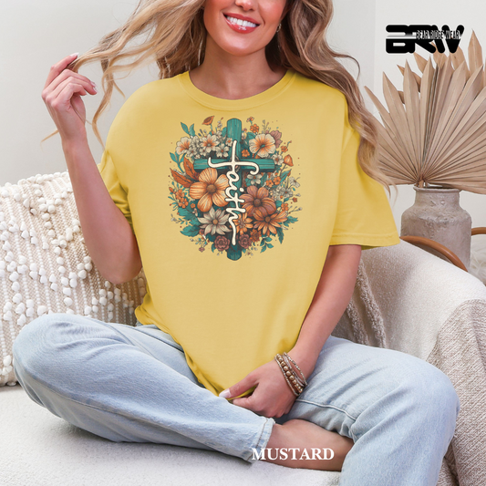 Woman wearing a yellow t-shirt with floral and cross design, sitting on a couch.
