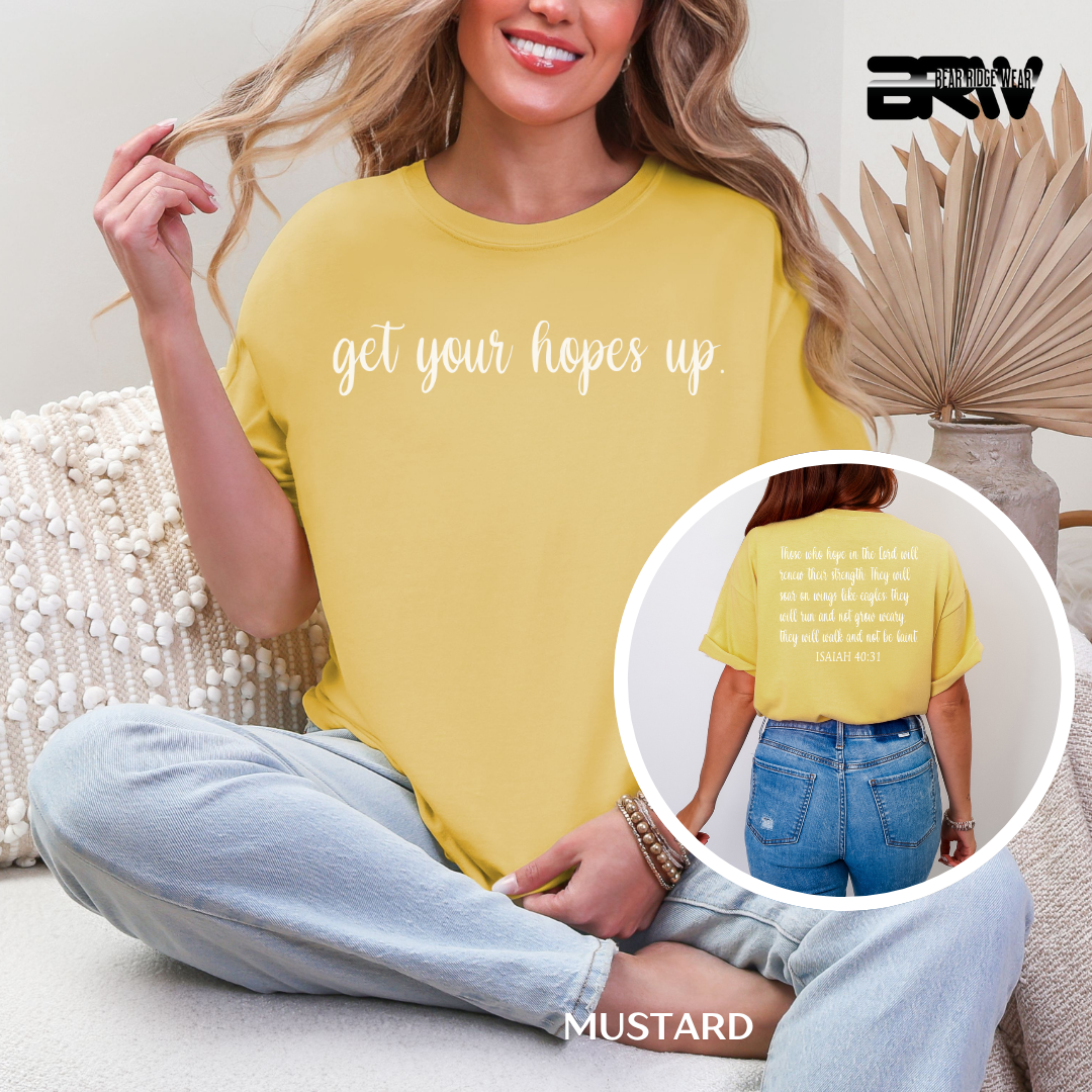 Woman wearing a yellow t-shirt with text, sitting on a couch.