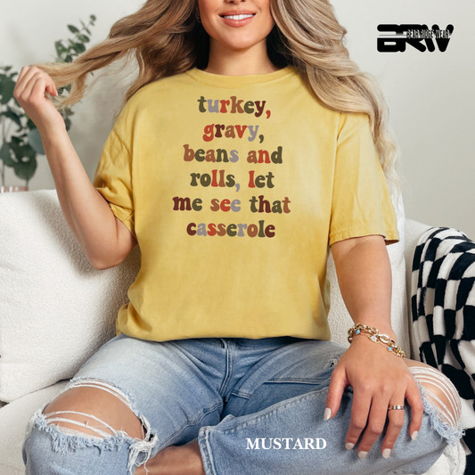 Woman wearing a mustard yellow t-shirt with text, sitting on a couch.